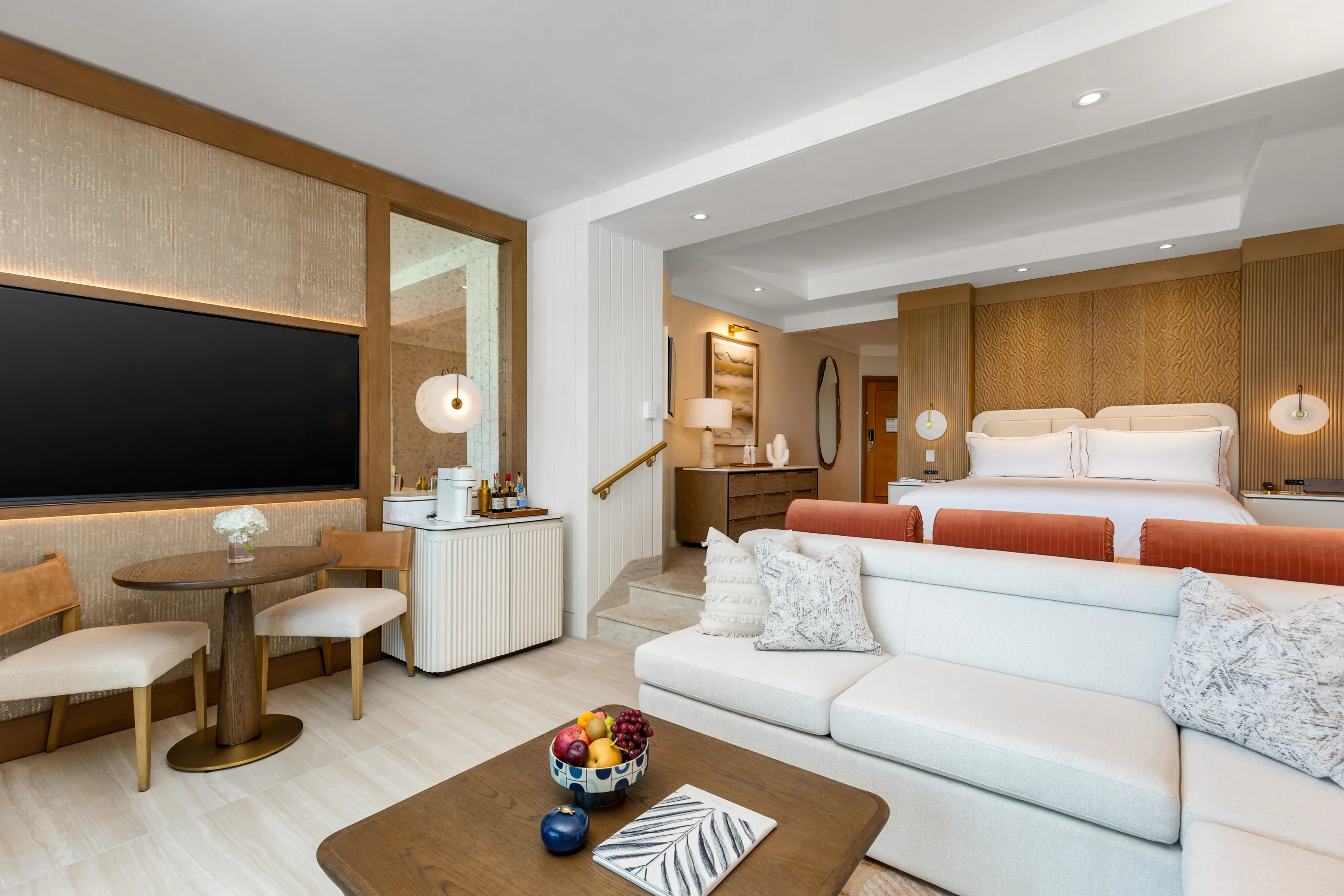 A renovated Cove suite: cream sofa, king bed and carved timber wall panels